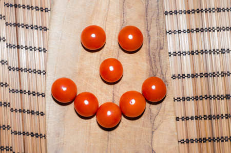 tomatoes on a cutting board that form a smileの写真素材