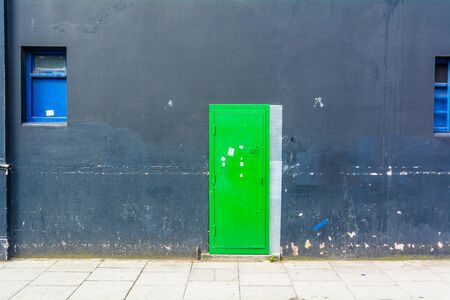 green door on gray wall with blue windows