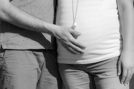 Pregnant woman: father's hands on the belly. Black and white imageの写真素材