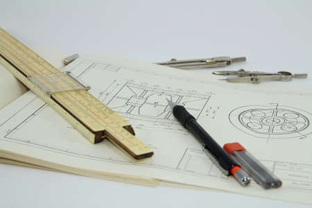 Slide rule and set of drawing instruments on a drawing isolated on white background の写真素材