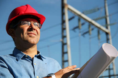 Engineer holding blueprints at an electrical substation の写真素材