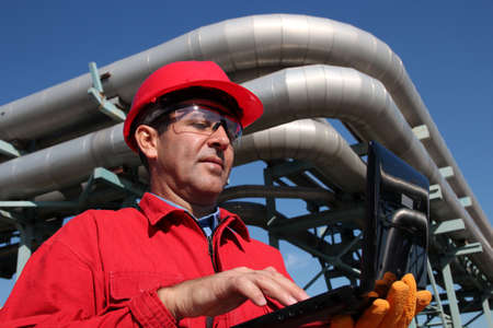 Industrial engineer inside oil and gas refinery using notebook 