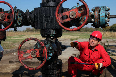 Oil worker pointing with his finger to oil field equipment の写真素材