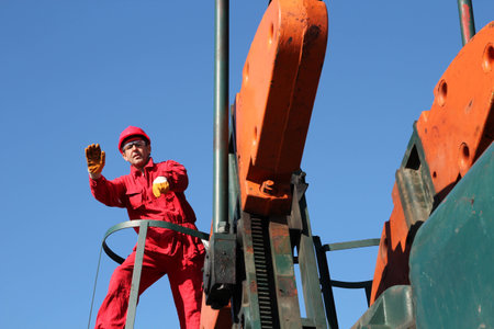 Oil worker on the pump jack doing a stop gesture with his handの写真素材