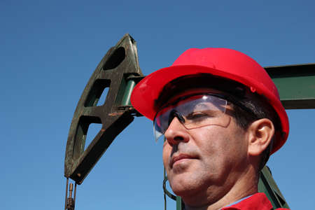 Portrait of petrochemical engineer at pump jack oil well.