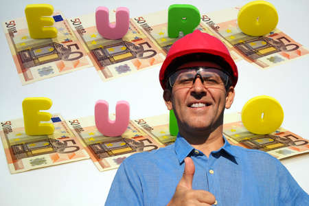 Smiling industrial engineer with red hard hat showing thumbs up in front of euro bills isolated on...