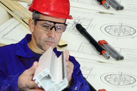 Mechanical engineer with red hard hat in front of drawing instruments and drawing. Mechanical...