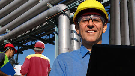 Group of engineers working with laptop and blueprint at oil refinery. Teamworkの写真素材