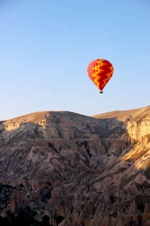 Hot air balloon flying over the mountains on a sunny dayの写真素材