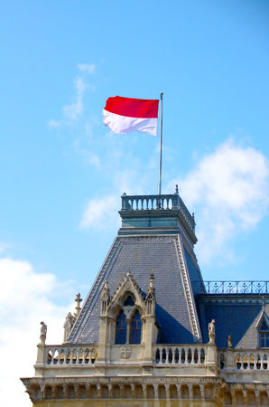 flag of poland on a dark colored mansard, in the background the blue sky with some white cloudsのeditorial素材