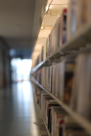 Books in a row located on shelves, background and front blurred. Ideal if you have a bookstore and want to promote discounts or if you like to read a lot. If you are a writer, announce the release of your next book on this attractive background and make it a literary bestseller.の写真素材