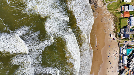 Top view of a beach with brown water, yellow sand and white wave foam. Ideal for lovers of beaches and waves on sunny daysの写真素材