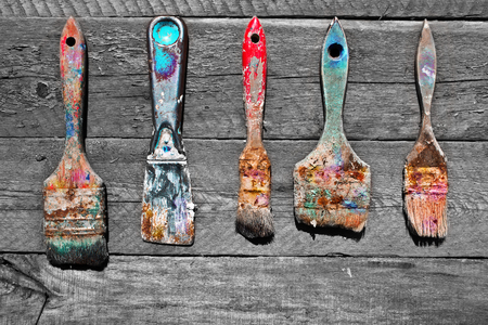 Soiled in a paint brush on unpainted natural wooden background. Old brushes for painting worksの写真素材