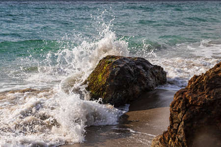 Wave breaking on rock near the shore in Malibu, California. Pacific Ocean in the background.の写真素材