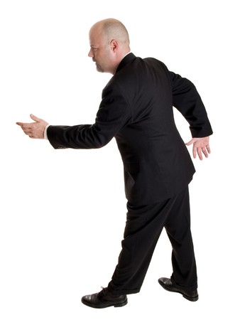 Stock photo of the side view of a well dressed businessman holding his hand out in a gesture as if pulling a rope or asking a woman to dance.  Full length, isolated white.の写真素材