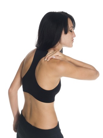 Isolated studio shot of a woman in a fitness outfit experiencing neck and shoulder pain.の写真素材