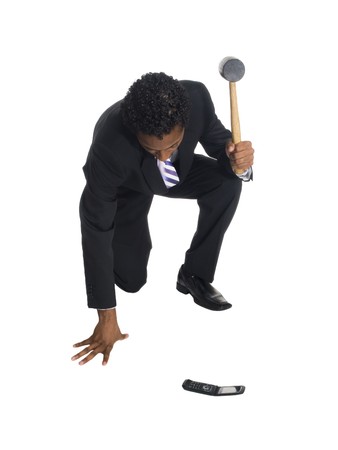 A well dressed businessman about to smash a cell phone with a hammer.の写真素材