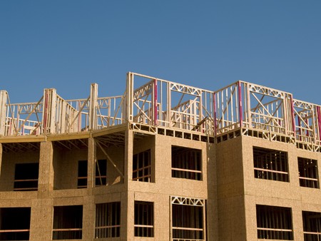 Urban construction site under a blue sky with white clouds.  Woodframe on a concrete substructure.