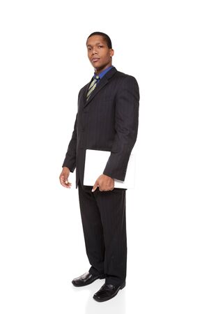 Isolated full length studio shot of a confident businessman looking at the camera while holding a laptop computer.の写真素材