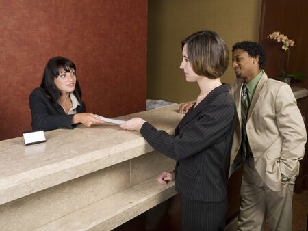 A hotel employee cheerfully welcomes guests.の写真素材