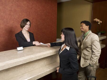 A hotel employee cheerfully welcomes guests.の写真素材
