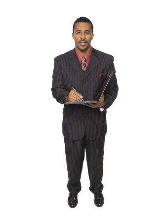 Isloated full length studio shot of an African American man looking at the camera while smiling and writing on his notepad.の写真素材
