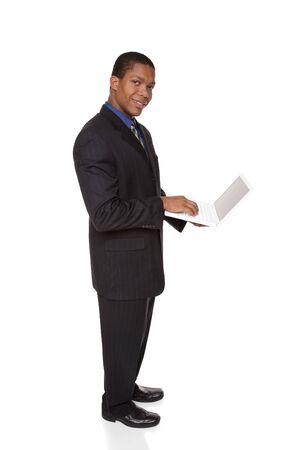 Isolated full length studio shot of a confident businessman looking at the camera while holding a laptop computer.の写真素材