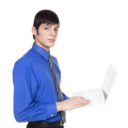 Isolated studio shot of side view of a Caucasian businessman standing and typing on a laptop computer while looking at the camera.の写真素材