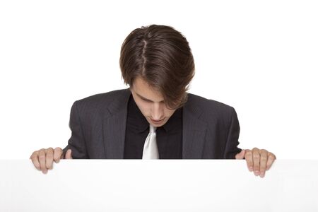 Isolated studio shot of a businessman looking down at a blank sign he is holding.の写真素材