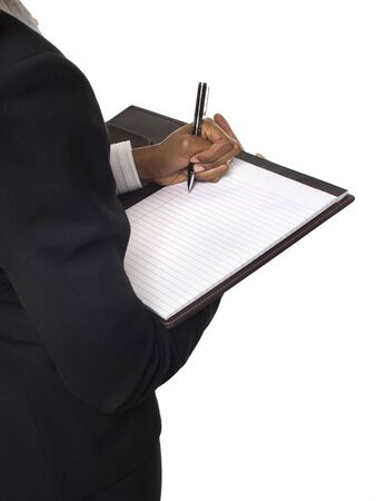 Isolated studio shot over the shoulder of a businesswoman writing on a notepad.の写真素材