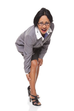 Isolated studio shot of a Latina businesswoman bending over and clutching her leg while looking at the camera.の写真素材