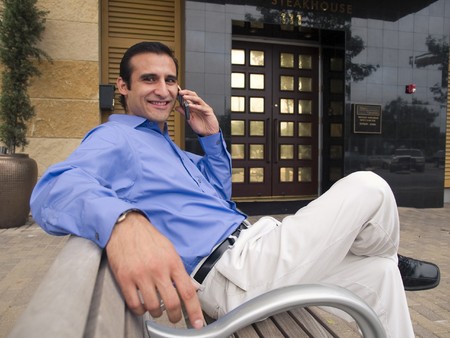 Handsome hispanic businessman chatting on a cell phone and smiling.の写真素材
