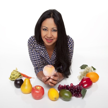 Isolated studio shot of a Latina woman examining fruits and vegetables, deciding what to eat for her healthy diet.の写真素材