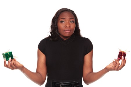 Isolated studio shot of an African American woman weighing the choice between red and green Christmas presents.の写真素材