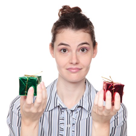 Isolated studio shot of a Caucasian woman choosing between red and green Christmas presents.
