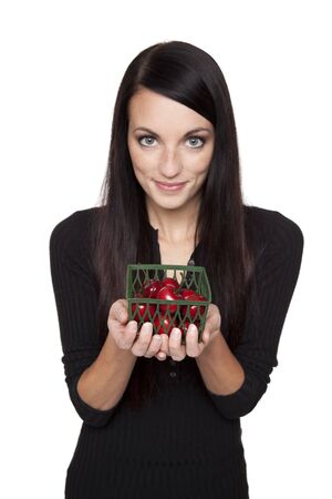 Isolated studio shot of a dark haired caucasian woman looking happily at vibrant fresh cherries.の写真素材