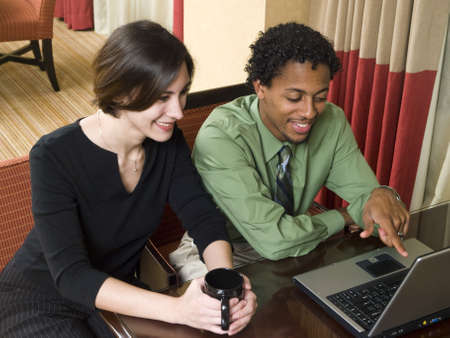 A business team cheerfully review good results on their laptop computer in a hotel room during a business trip.の写真素材