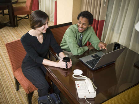 A business team cheerfully review good results on their laptop computer in a hotel room during a business trip.の写真素材