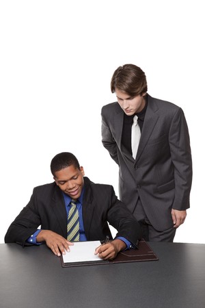 Isolated studio shot of two businessmen writing notes on a notepad at a conference table.の写真素材