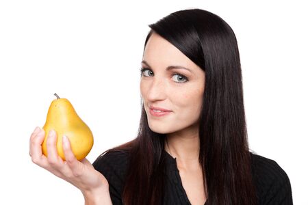 Isolated studio shot of a dark haired caucasian woman looking happily at a vibrant fresh pear.の写真素材