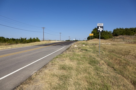 A view down East FM 3267 under a clear blue sky, looking over drought stricken grass.の写真素材