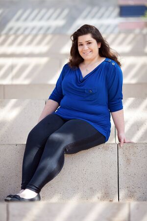 Stock photo of a casually dressed woman sitting in an outdoor urban environment.の写真素材