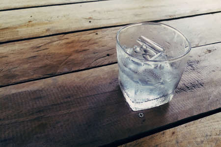 Ice in a glass placed on a wooden floor and the feeling of a vintage.の写真素材