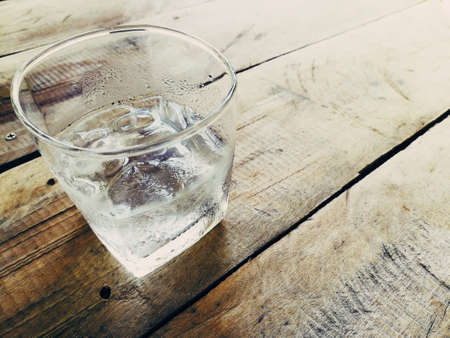 Ice in a glass placed on a wooden floor.の写真素材