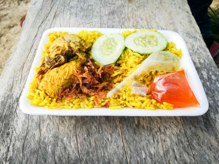 Yellow rice with yellow chicken on the wooden bench in morning.の写真素材