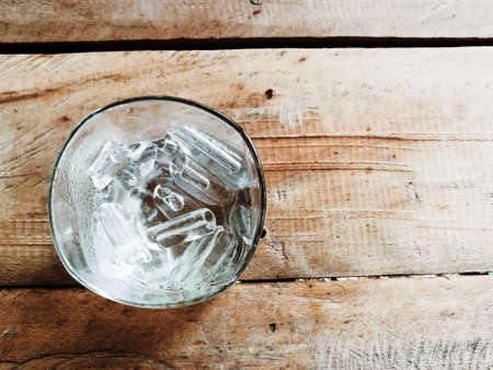 Close up ice in a glass placed on a wooden floor.Top view vintage style.の写真素材