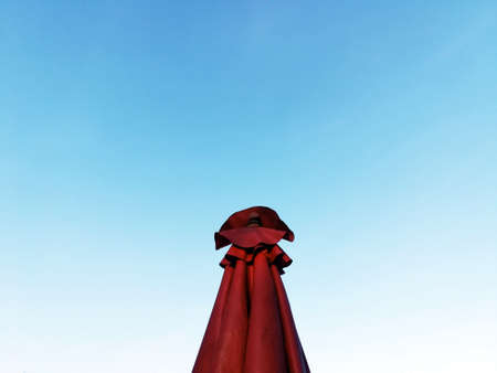 Red umbrella with blue sky background in ladies concept.If you try to imagine this image, then it is similar to a woman standing in red dress.の写真素材