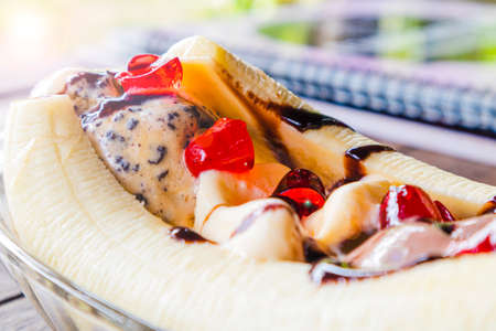 Close up tropical delicious banana split ice cream dessert with chocolate drizzle.