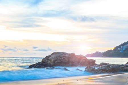 Beautiful long exposure seascape with rock on beach and bright sky in the morning.の写真素材