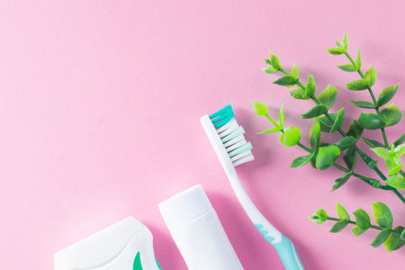 Pastel pink background with cleaning tools for oral and dental health care such as toothbrush, toothpaste, and floss. Concept: lifestyle and daily routine for a healthy mouth and teeth.の写真素材